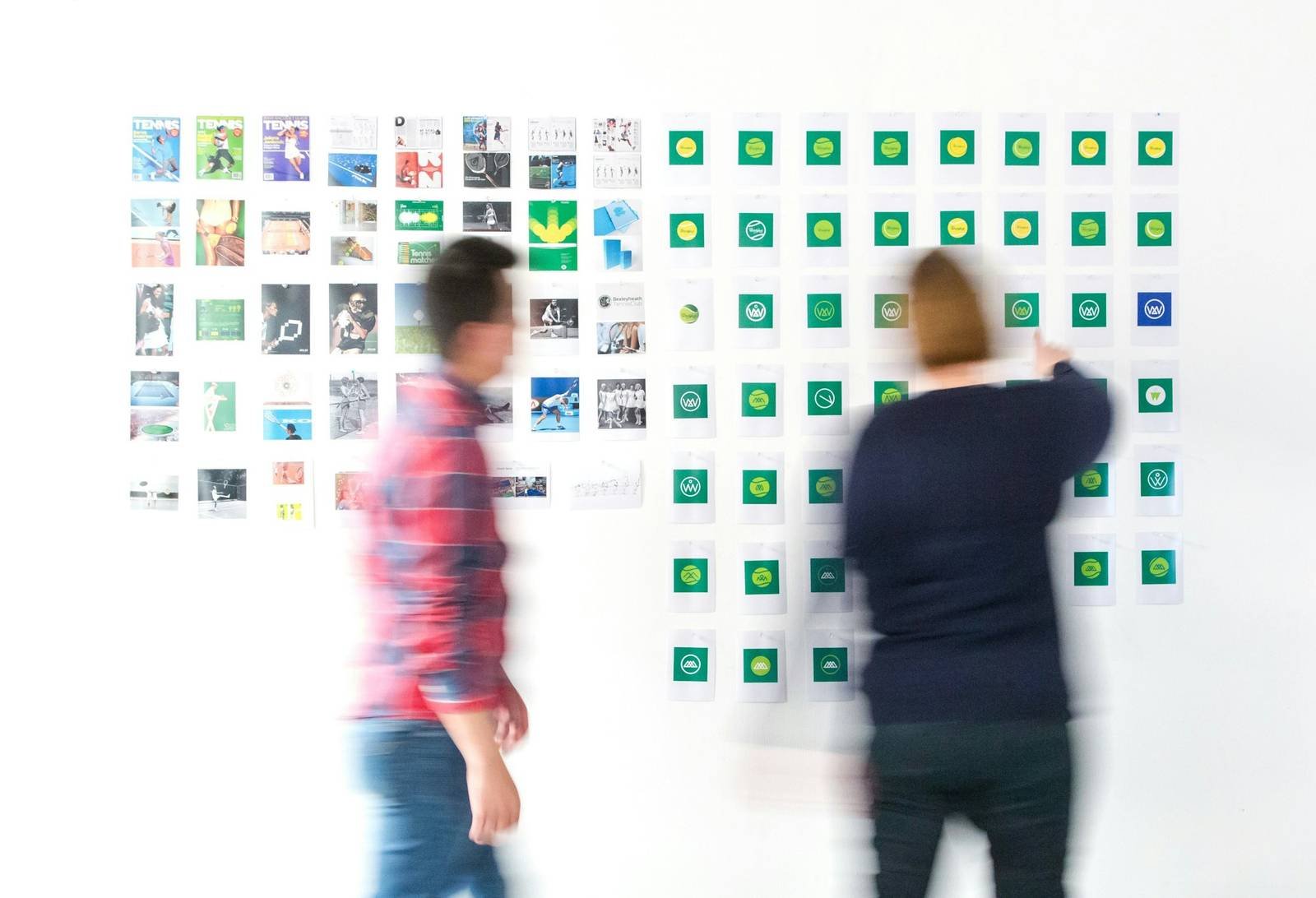 Designers arranging printed studies on a critique wall
