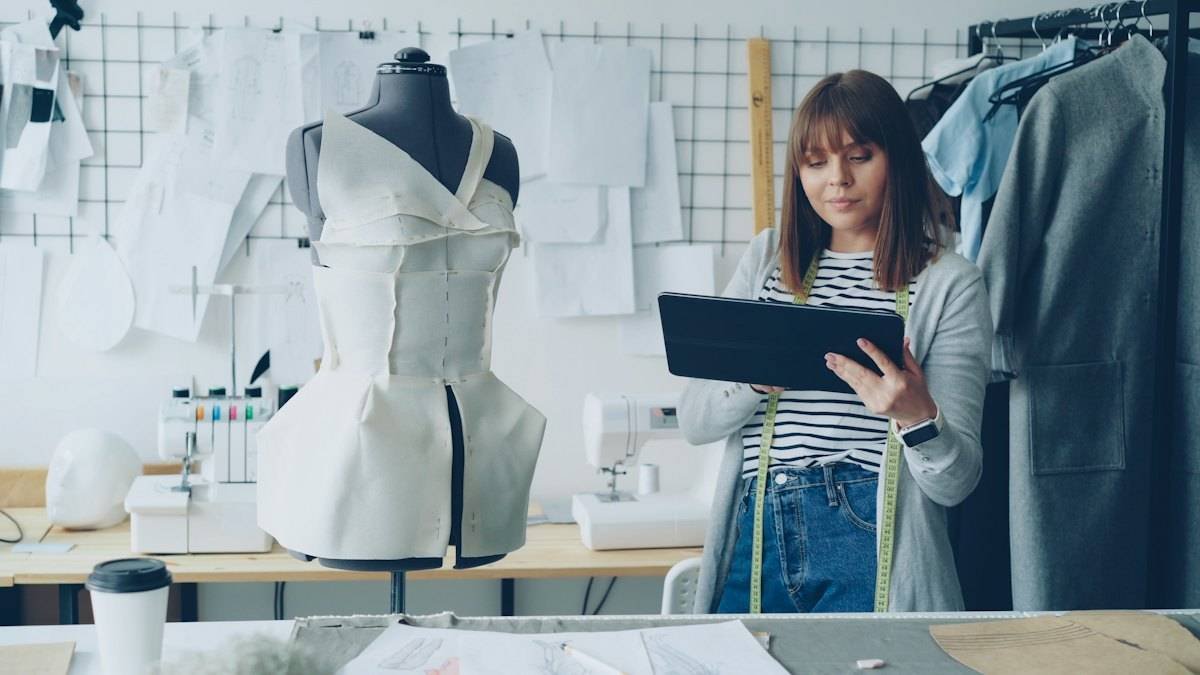 Designer reviewing a garment design on a tablet beside a dress form