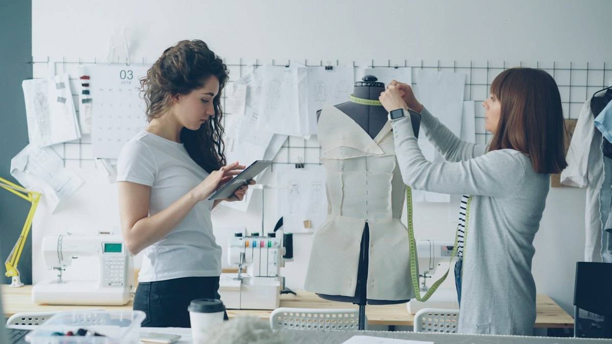 Two fashion designers fitting a toile on a dress form